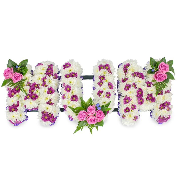 This heartfelt floral design spells MUM in large sculpted letters, each letter hewn from a plush mound of pristine white chrysanthemums that give the piece its soft, billowy texture and luminous, sympathetic tone. Carefully placed magenta and deep purple spray blooms are scattered through the white to create a tasteful, irregular pattern that enriches the surface without overpowering the overall serenity. The composition is accentuated by three clusters of pink spray roses: one modest cluster at the upper left of the first M, a more abundant cluster nestled into the low curve of the U, and a matching bloom at the upper right of the final M - each accompanied by dark green foliage and graceful fern fronds that add movement and depth. Small blue accent flowers are threaded through the greenery, offering tiny points of contrast like dewdrops across a garden of white. A slender, dark horizontal connector links the letters at their base, discreetly stabilising the arrangement while keeping attention on the floral shapes. In soft morning or chapel light the chrysanthemums appear almost luminous, and the gentle fragrance of roses mingles with the mild earthiness of the greens, creating an atmosphere of remembrance and calm. Crafted with sensitivity for funerals, wakes and memorial services, this bespoke tribute is the kind of design families in Chinatown and nearby Covent Garden ask for when they want to honour a mother with both dignity and tenderness. Its balanced colour story - white, magenta, pink and green with tiny blue notes - communicates love, respect and cherished memories without excess.