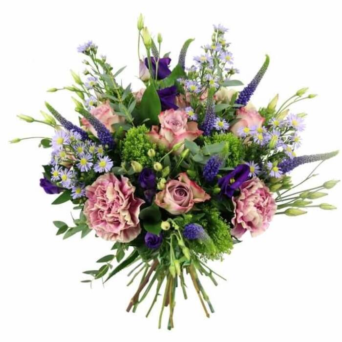 A beautifully composed, hand-tied bouquet in a harmonious blend of pink, mauve, lilac, and deep purple fills this image, photographed against a pure white background that highlights its colours and textures. At the heart are soft pink roses, with some blooms more open and revealing intricate swirls of petals, while others remain partly closed, adding variety and a sense of unfolding life. Many petals carry gentle shifts of tone, from deeper blush at the centre to paler, almost creamy edges, lending dimension and elegance. Interspersed with the roses are generously sized carnations in dusty rose and purple-mauve shades, their densely ruffled petals forming lush, cushion-like blooms that add weight and luxurious softness. Shooting up through the rounded silhouette, elongated spires of deep lavender-blue Veronica bring height and a touch of wild grace, their tapered forms and tiny florets providing a striking contrast in texture. Nestled among these are lisianthus flowers in rich, velvety purples, some fully opened into cup-shaped blossoms, others still in smooth buds, enhancing the sense of depth and maturity. Fine sprays of aster-like flowers in delicate lavender and periwinkle punctuate the arrangement, each little daisy-like bloom with a pale yellow centre that sparkles lightly among the richer tones. Wrapped around and peeking through the blooms, lush greenery offers both structure and freshness: vivid lime-green, almost chartreuse filler reminiscent of green trick dianthus or sedum stands out vibrantly, while muted sage and silvery eucalyptus leaves introduce calm, cool notes and varied leaf shapes. From a slightly overhead perspective, the stems can be seen gathered tightly at the base, neatly trimmed and tied in the classic hand-tied style many Chinatown florists favour for easy vase placement. This bouquet feels equally at home as a birthday surprise in a flat above Wardour Street or as a romantic anniversary gift delivered to a restaurant table in Chinatown or nearby Soho.
