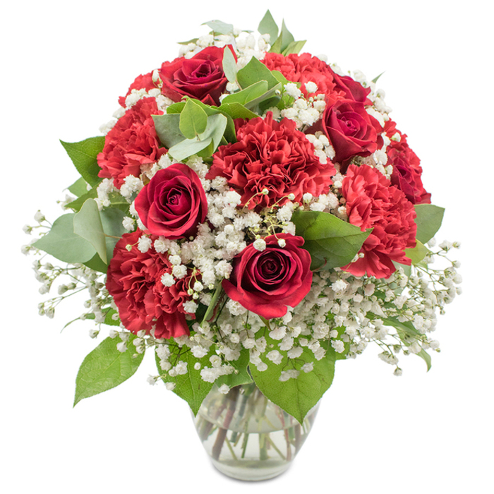 A sumptuous bouquet of red and white blooms rises from a clear glass vase, set against a stark white background that throws every stem, petal, and leaf into sharp relief. Deep red roses, with their velvety petals spiralling inward, form the emotional core of the design, each flower exuding warmth and intensity that feel perfectly at home amid the lively streets of Chinatown. Around them, clusters of red carnations expand the composition, their densely ruffled petals overlapping to create a layered, tactile surface that seems almost touchable, like the intricate fabrics displayed in nearby market stalls. Woven throughout these passionate red flowers is an airy veil of white baby's breath, its tiny, cloud-like blossoms softening the arrangement and adding a sense of innocence and grace. The combination of rich red and fresh white creates a striking contrast reminiscent of festive decorations strung above Gerrard Street during celebrations, capturing both joy and tenderness in a single view. Fresh greenery adds depth and structure: dark rose leaves give a sturdy, classic frame, while round eucalyptus leaves add a cool, silvery-green accent that feels contemporary and calming. The glass vase is simple and unfussy, with a slightly flared rim, allowing the viewer to see the neatly bundled stems in clear water, a quiet nod to professional craftsmanship. The bouquet has been shaped into a full, rounded dome so that it appears generous from every angle, making it ideal as a centerpiece for a Chinatown restaurant table, a romantic surprise in a nearby Soho apartment, or a thoughtful gift sent to mark an anniversary, engagement, or heartfelt reunion in the West End.