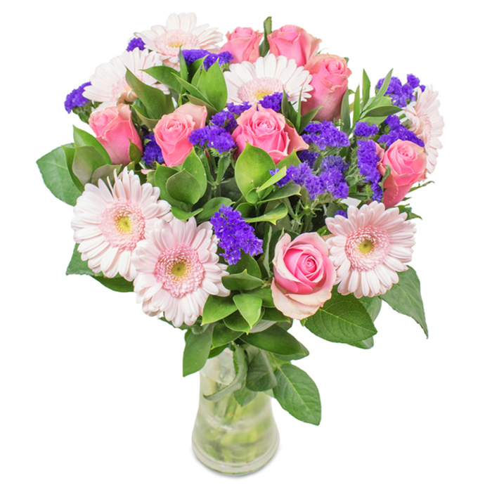 An exquisite, thoughtfully arranged bouquet from Chinatown, London, sits gracefully in a clear, cylindrical glass vase, posed against a luminous, uncluttered white backdrop. Central to this arrangement are roughly 7-9 roses in shades of soft to medium pink, their petals spiralling gently-some still tightly curled, others opening in delicate layers that capture soft overhead light. Intermingled are 5-7 pale pink Gerbera daisies, distinguished by their round, generous heads and subtle, ivory-tinged centres, echoing the floral motifs of Chinatown's cultural festivals. Accents of vivid purple statice thread through the design, adding dynamic depth and a striking richness of colour, while luxurious, deep green foliage surrounds the ensemble, infusing volume and a touch of verdant abundance. The clear glass vase reveals crisp stems and water, suggesting ideal freshness, like flowers just unwrapped from a delivery on Lisle Street. Suitable for birthdays, anniversaries, Mother's Day, or simply to bring a sense of joy and celebration to a home or office in busy Chinatown, this artful combination of roses, Gerbera daisies, and purple statice radiates affection, care, and everyday elegance-reflecting the florist's skill and vibrant local culture.