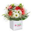 With joyful spirit and understated glamour, this Chinatown bouquet makes a radiant impression in a modern white gift bag-its sturdy ribbons echoing the careful attention found in the area's best floral shops. Flouncy coral and pastel peach carnations, highlighted by touches of vibrant red, create a lively tableau, their petals almost glowing under the soft light that defines the image. Clustered bright white daisies with sparkling green-yellow centres gently lift the tone, suggesting the feeling of early spring walks through Chinatown's secret courtyards. Wisps of baby's breath scatter a dreamy, romantic texture throughout, while a glance to the left reveals softly closed buds streaked with purple, hinting at moments soon to unfold. Lush, deep green foliage forms a stylish, sturdy cradle at the base, the glossy leaves enhancing the freshness and fullness of the bouquet. The clean white background strips away distraction, letting each blossom's colour and detail shine-calling to mind the carefully balanced aesthetics found throughout Chinatown. Whether gifted for birthdays, festive celebrations, or as a spontaneous gesture, this arrangement is a heartfelt testament to the neighbourhood's tradition of beauty and delight in giving.