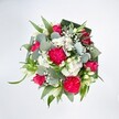 A vibrant, rounded bouquet is photographed from above against a crisp white background, the clean setting making every colour in the arrangement glow with clarity. At the heart of the design, rich hot pink carnations unfurl in layers of finely ruffled petals, their frilled edges creating a luxurious, almost velvety texture that seems to spill outward. Nestled among them are deep pink and fuchsia roses, some fully open with elegant, spiralled centres, others still in tight, hopeful buds that hint at days of beauty still to come. Clusters of small white spray chrysanthemums and other daisy-like blossoms are scattered through the bouquet like soft clouds, their tiny petals forming rounded cushions of brightness. Delicate sprays of white baby's breath weave between the larger flowers, adding a misty, romantic lightness, while a few slender white buds, reminiscent of alstroemeria or lily blooms, contribute a quiet note of purity and grace. Surrounding the flowers, a generous collar of foliage gives the bouquet structure and depth: rounded, silvery-green eucalyptus leaves introduce a cool, calming tone, contrasting with the vivid pinks, while long, bright green blades and darker, broader leaves-expertly folded in a structured, almost architectural way-frame the design like a living wreath. The lighting is soft yet clear, catching the satin sheen of the petals and the gentle gloss of the greenery, so every stem appears freshly cut, as if arranged moments ago in a Chinatown florist's studio just off Gerrard Street. The overall impression is joyful, polished, and celebratory, a bouquet that feels perfect for birthdays, congratulations, or any moment when you want to send a burst of colour and affection across central London.