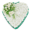 A large heart-shaped floral tribute is shown against a plain white background, its quiet elegance capturing the essence of sympathy and remembrance. The heart is filled entirely with tightly packed white chrysanthemums, each flower small yet full, combining to form a smooth, cushioned surface that appears almost like a soft quilt of petals. The white blooms, with their subtly ruffled edges, create an impression of calm purity and are often chosen to express peace and respectful farewell. Around the edge of the heart runs an emerald green satin ribbon, expertly pleated into delicate ruffles that form a scalloped frame. The ribbon's gentle sheen defines the heart's outline with a rich, dignified contrast to the velvety chrysanthemums, adding structure and a touch of ceremonial grace. Set into the upper left curve of the heart, a thoughtfully composed floral cluster becomes the main focal point. Two open white roses, their creamy petals spiralling outward in beautiful layers, rest prominently on the surface, symbolising deep love and honour. They are surrounded by smaller white flowers-likely freesias or similar blooms-and a few softly rounded buds, adding variety in shape and height. Lush green foliage, including broad glossy leaves and feathery, fern-like fronds, encircles the roses and extends lightly over the chrysanthemum base, giving a sense of gentle movement. The overall mood is serene and contemplative, an arrangement designed to support grieving families and friends during funeral services or memorials around Chinatown, Piccadilly, and Soho. It is the sort of traditional heart tribute local florists create with care when words feel insufficient, allowing flowers to carry the message of sympathy and remembrance.