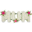 The photograph presents a tender MOM floral tribute, crafted with the kind of precision and respect one might expect from a long-established Chinatown flower shop. The three large block letters are completely filled with tightly packed white blooms-likely chrysanthemums-creating a textured, cushion-like surface that feels both gentle and reassuring. Their petals overlap in countless layers, forming a seamless field of white that glows softly against the neutral background. Along the bottom edge of each letter, a dark green frame and matching ribbon edging can be seen, giving the design its clean silhouette and reliable structure, ready to be placed at a funeral service or memorial vigil. To add warmth and personality, three carefully balanced floral accents of pink roses and ferns have been added. At the top left of the first M, a cluster of deep fuchsia and pale pink roses opens fully among sprays of delicate, fern-like foliage. A similar arrangement of roses and greenery is set low between the O and the second M, uniting the letters with a gentle arc of colour. The third cluster rests on the upper right arm of the final M, creating symmetry and completing the visual story. The contrast between the pure white base and the vibrant pink roses symbolises both reverence and affection-a fitting tribute for a beloved mother connected to the close-knit communities and bustling streets around Chinatown. One can almost sense the soft fragrance of the roses mingling with the clean scent of fresh chrysanthemums, offering quiet comfort and a final, loving message in bloom.